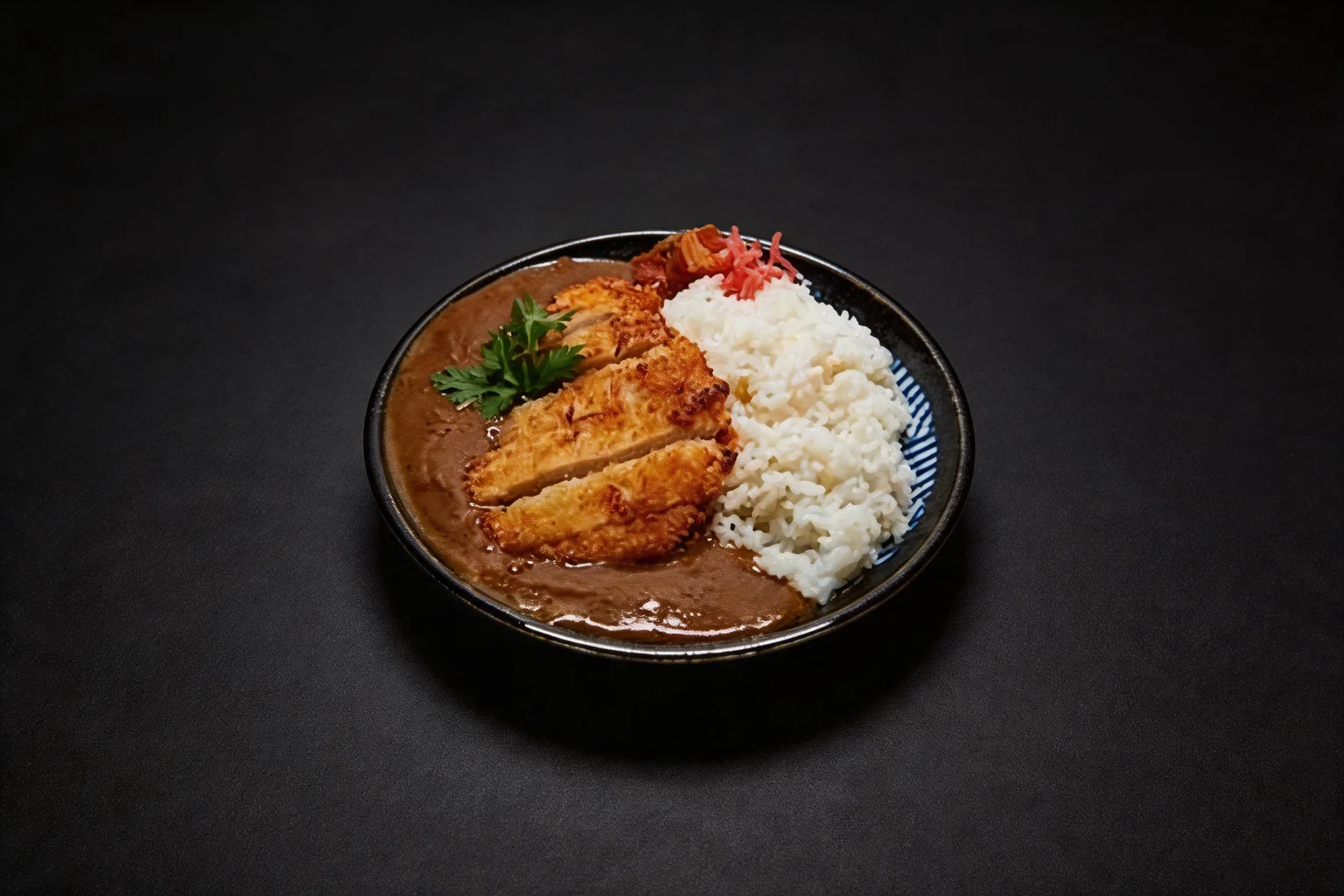 Katsu curry dans une assiette creuse noire et bleue, fond sombre.