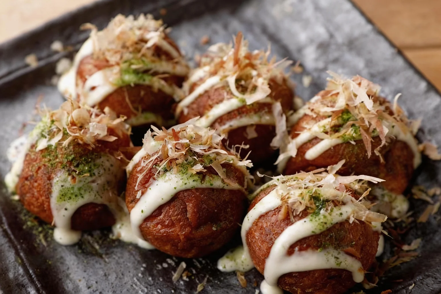 Takoyaki sur un plat gris, table en bois.